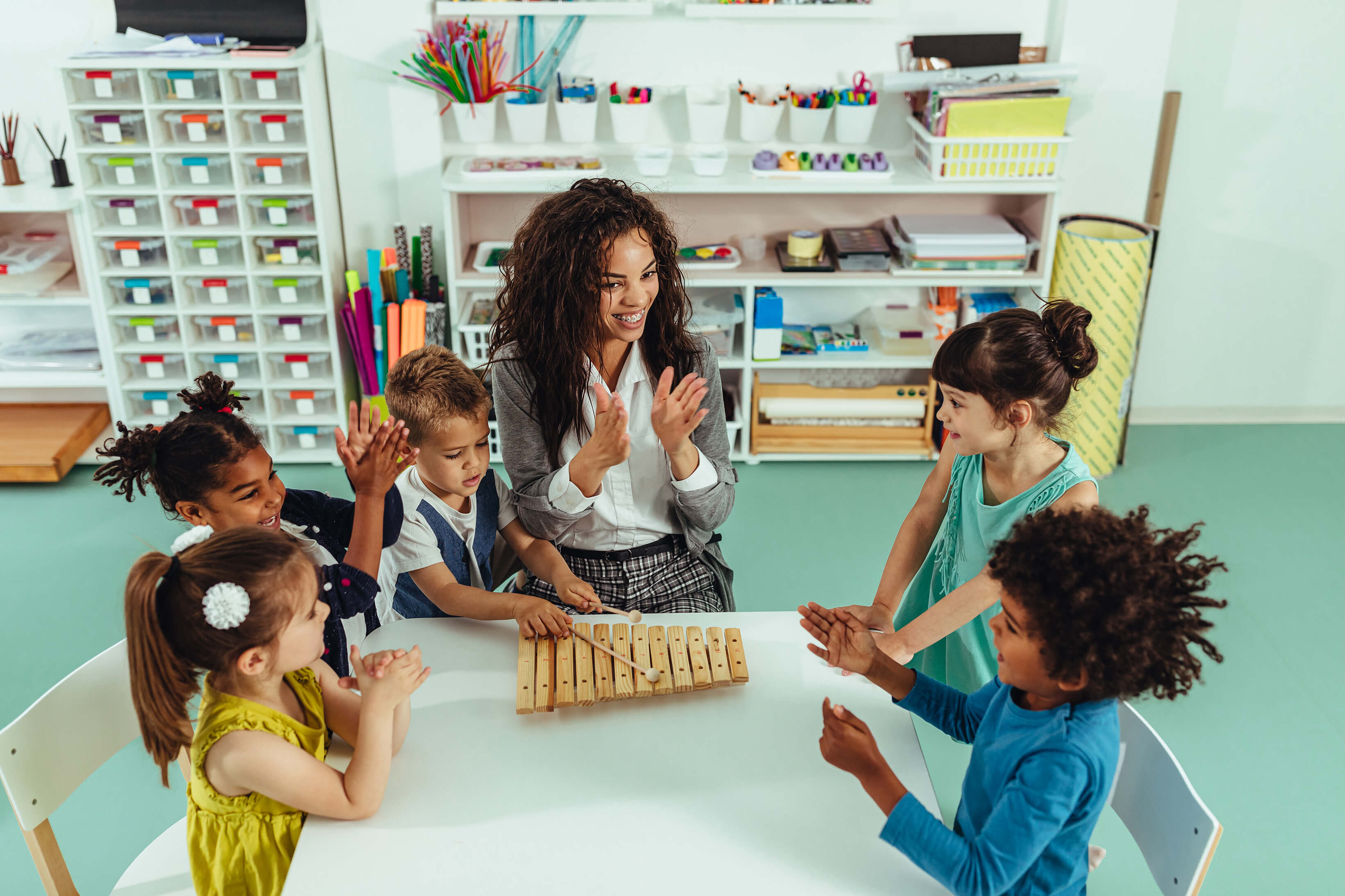 Teacher and a group of children sitting around a table.