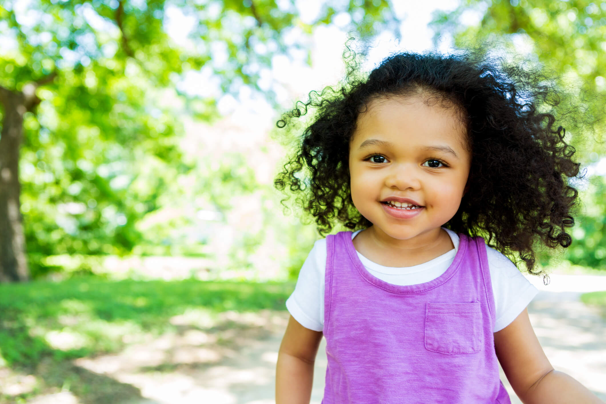 A child in a purple shirt, walking in the park.